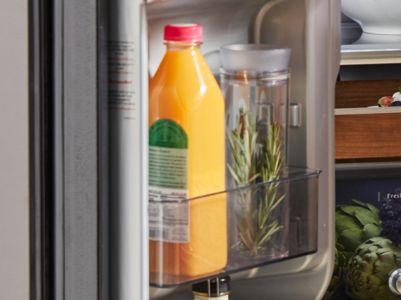 Jar of fresh rosemary in a refrigerator next to a bottle of orange juice Jar of fresh rosemary in a refrigerator next to a bottle of orange juice