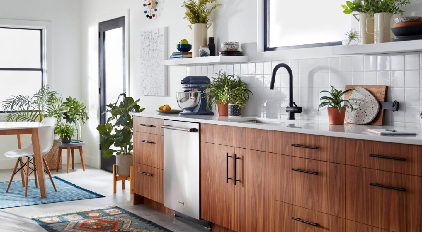 Blue KitchenAid® Artisan stand mixer sitting on white countertop in white modern kitchen with open shelving and brown wooden cabinets. Blue KitchenAid® Artisan stand mixer sitting on white countertop in white modern kitchen with open shelving and brown wooden cabinets.