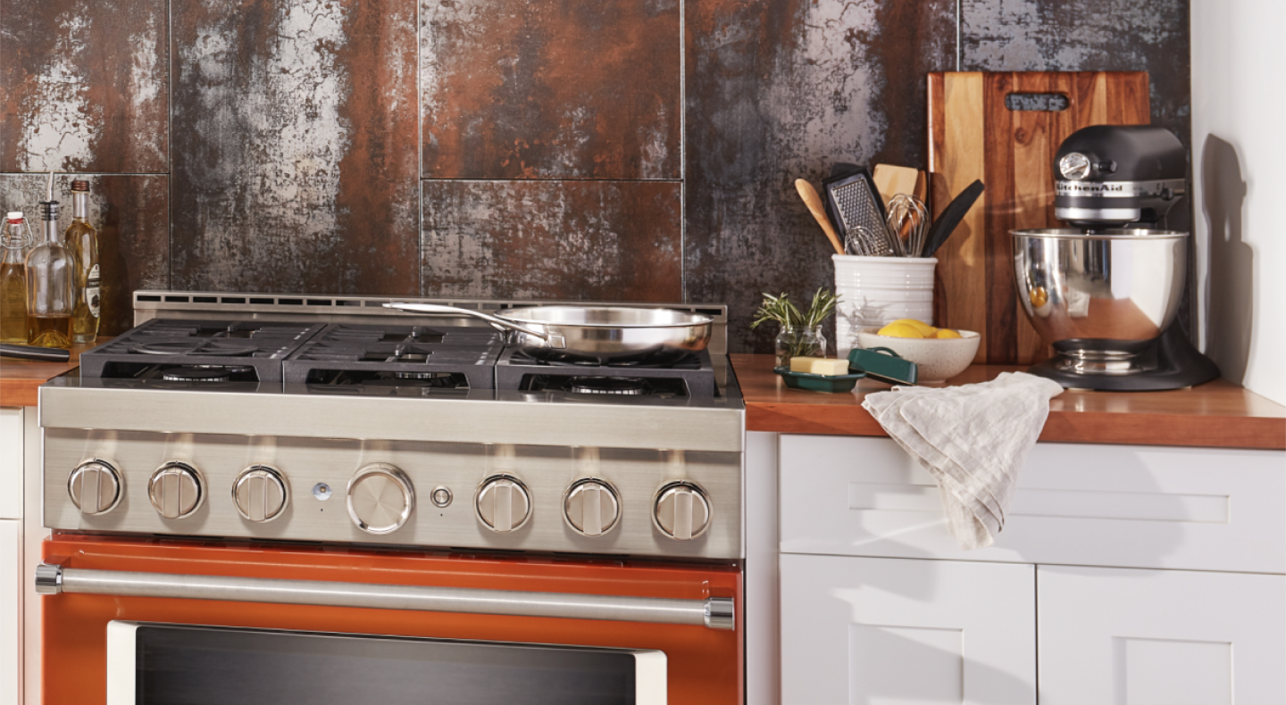 A black KitchenAid® stand mixer on the counter next to a gas range. A black KitchenAid® stand mixer on the counter next to a gas range.