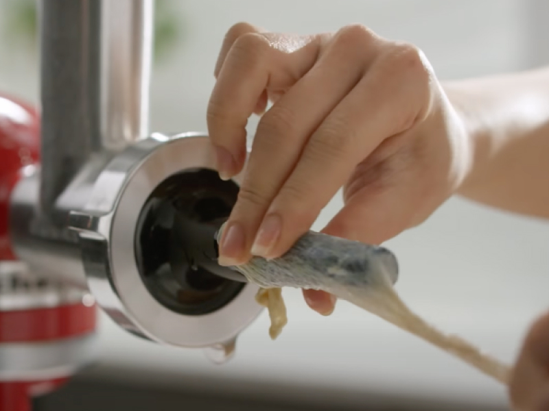 Person adding casing to the sausage stuffer tube