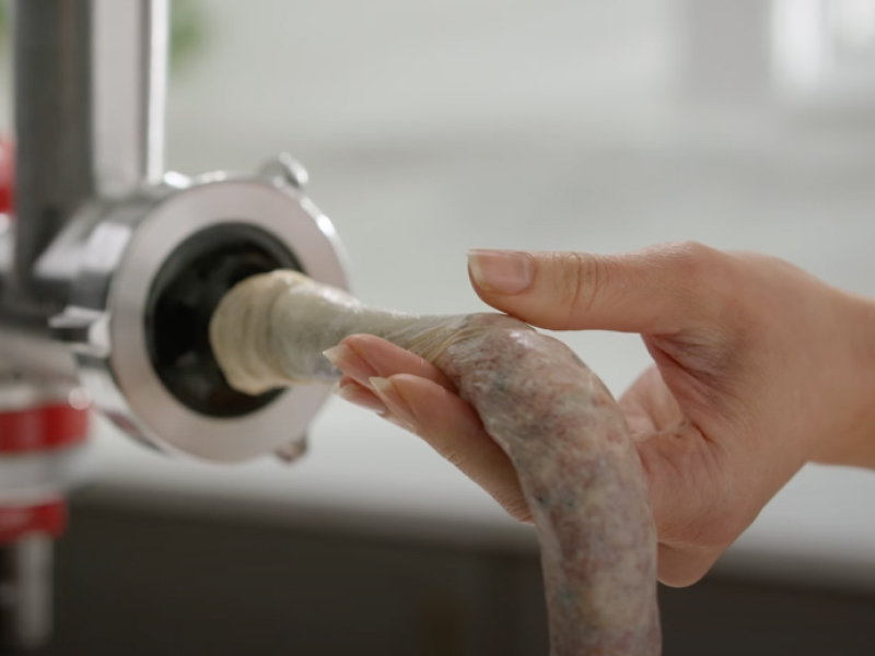 Person feeding ground meat into the casing