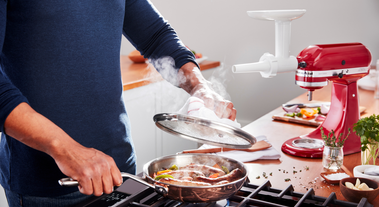 Person preparing food in a skillet on a cooktop