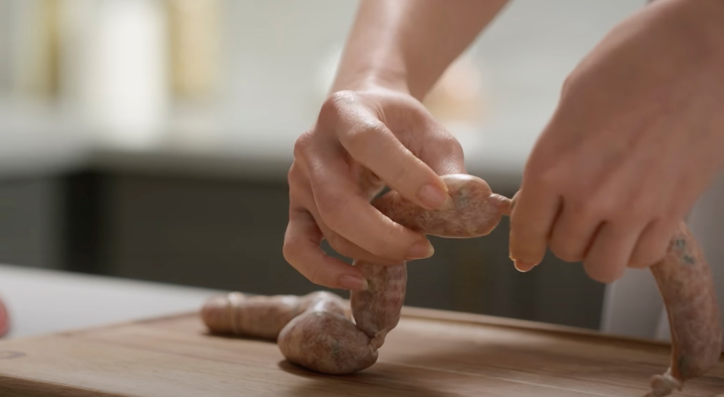 Person linking sausages Person linking sausages