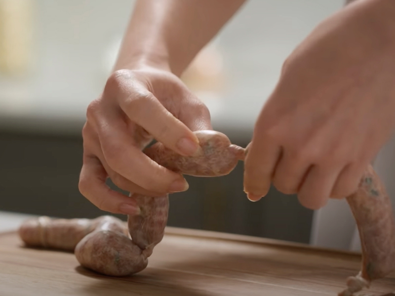 Person linking sausages Person linking sausages