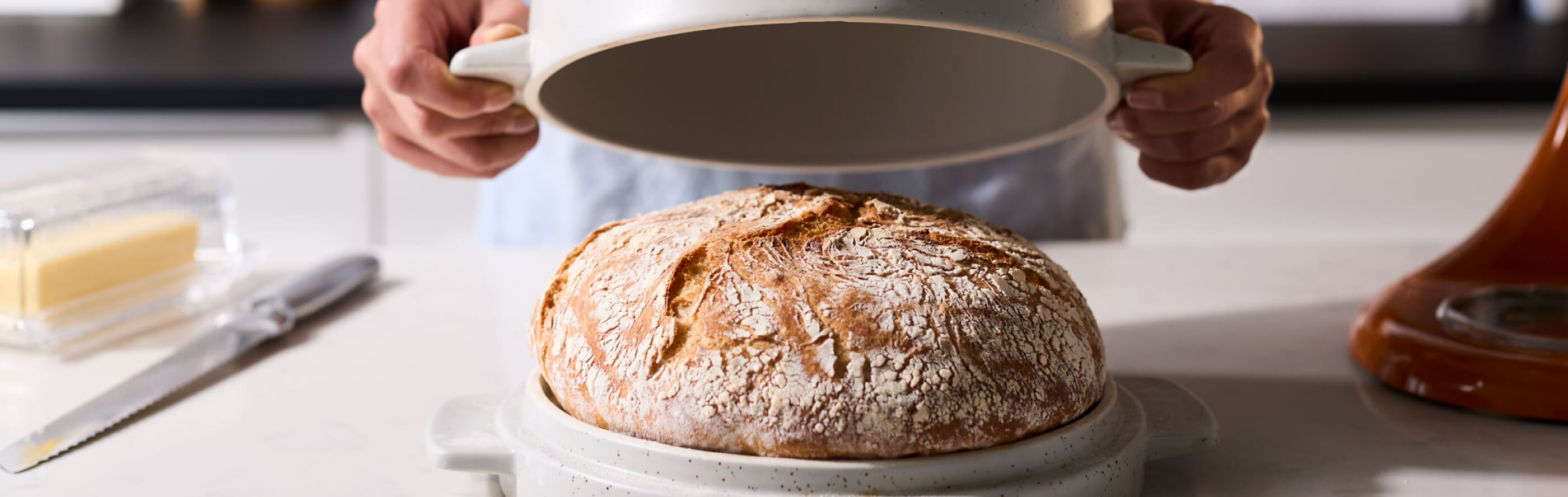 Bread in a bread bowl with person removing lid