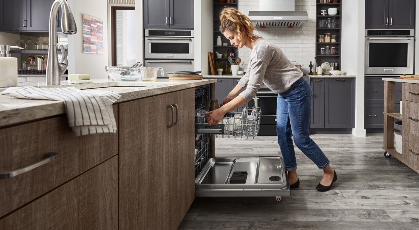 A person adjusting the second rack of a dishwasher