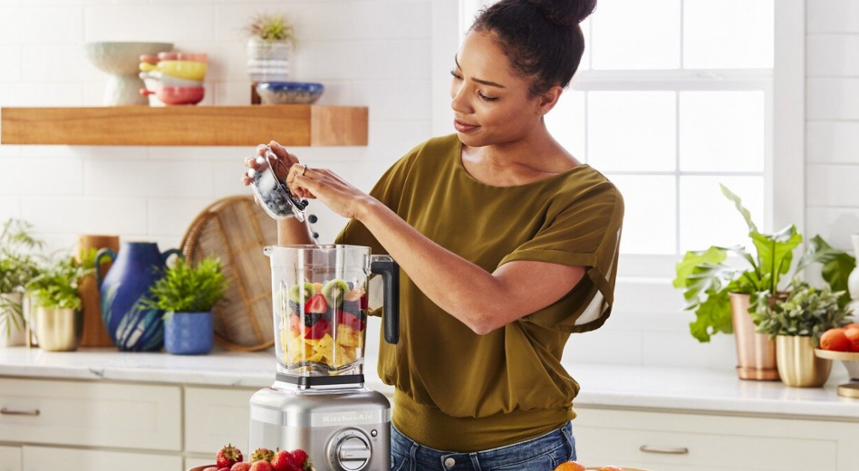 Woman preparing a fruit smoothie with a KitchenAid® blender Woman preparing a fruit smoothie with a KitchenAid® blender