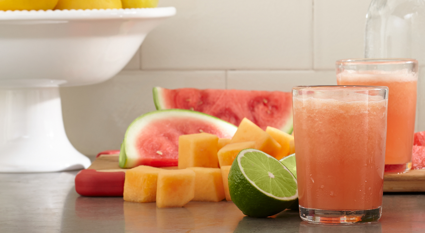 Glasses of fresh juice next to assorted fruit pieces Glasses of fresh juice next to assorted fruit pieces