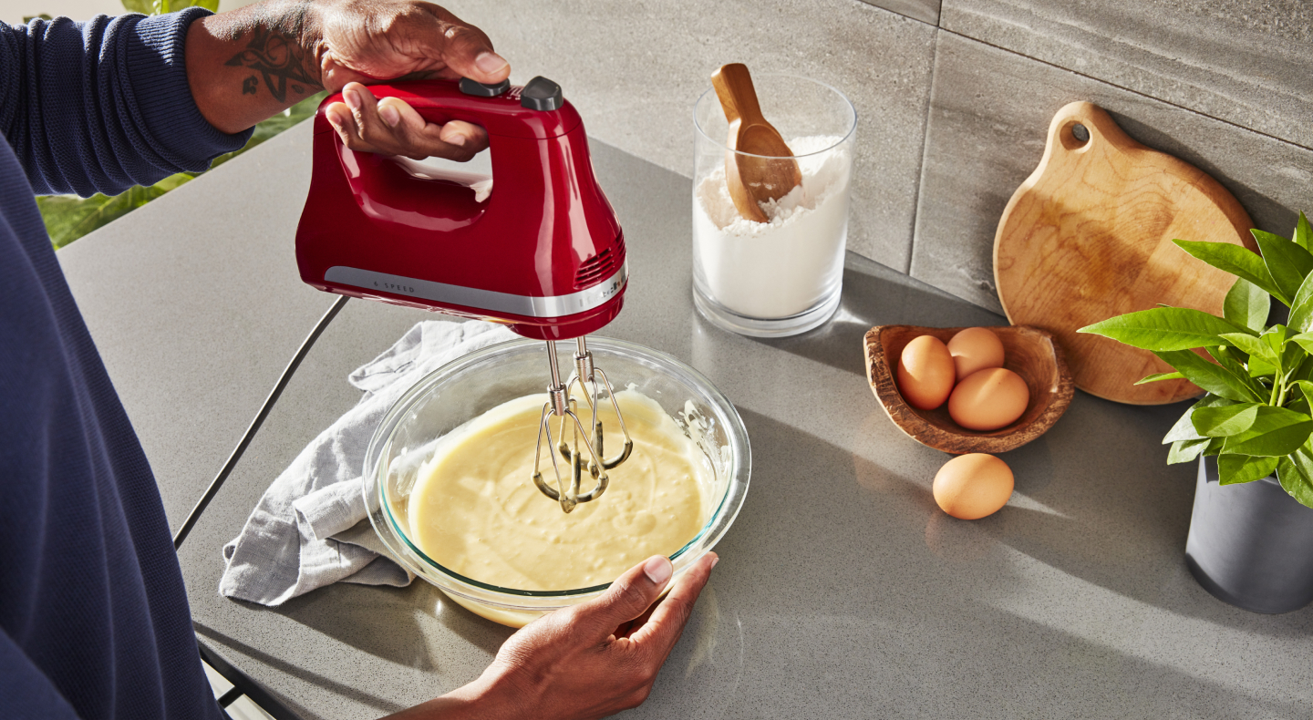 Person using KitchenAid® hand mixer over bowl of batter Person using KitchenAid® hand mixer over bowl of batter
