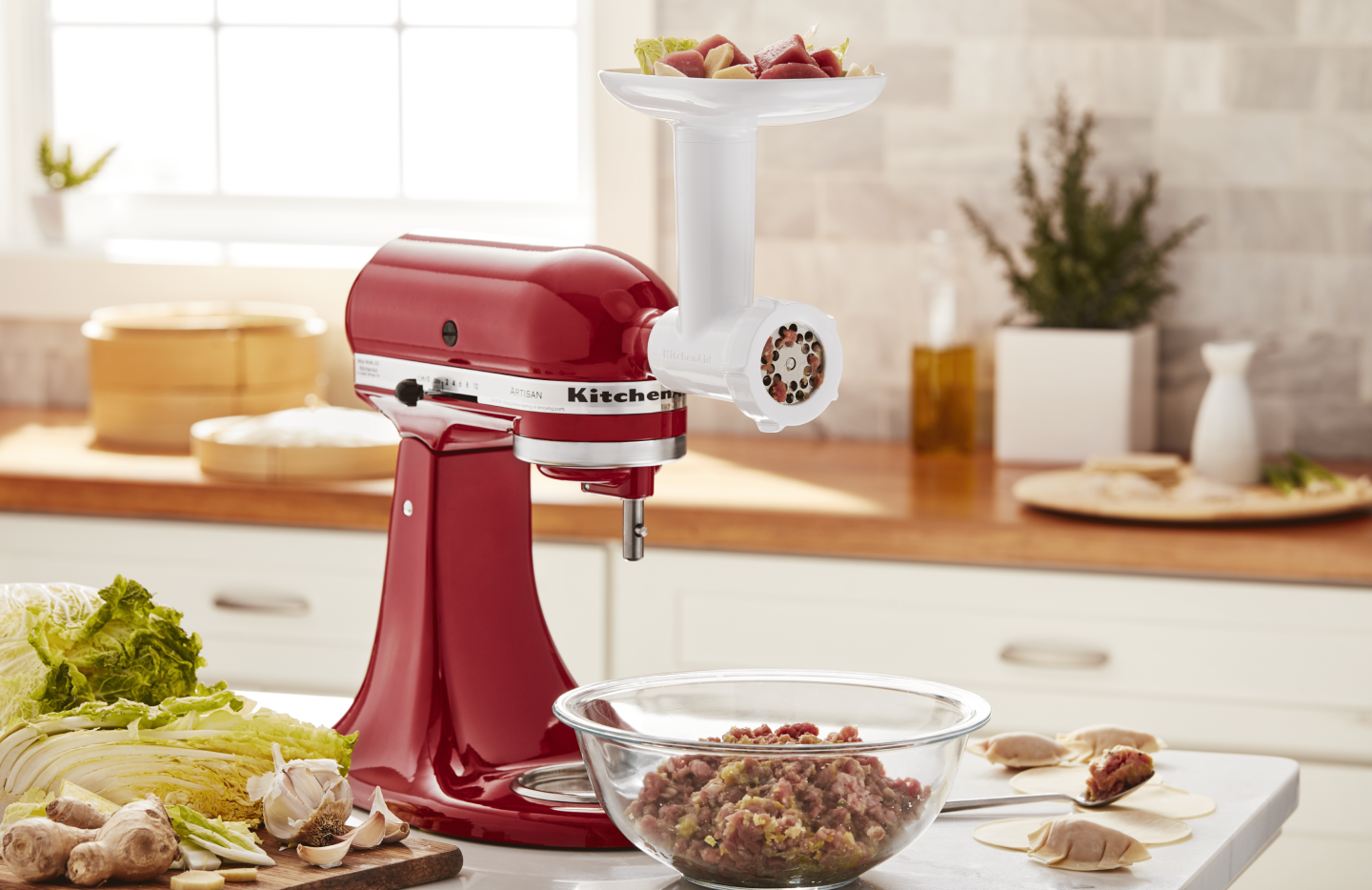 Red KitchenAid® Stand Mixer with white food grinder attachment grinding meat Red KitchenAid® Stand Mixer with white food grinder attachment grinding meat