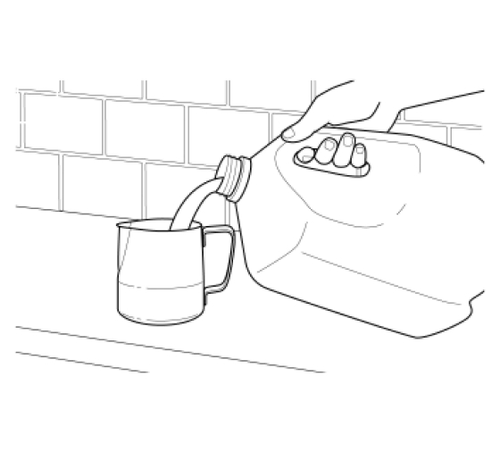 Hand pouring milk from a jug into frothing pitcher