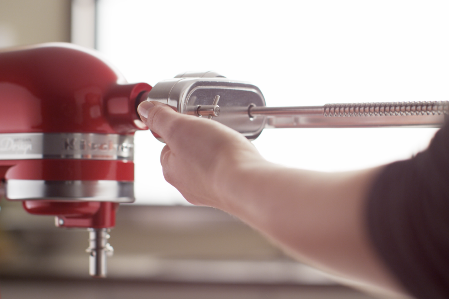A person inserting an attachment into a stand mixer. A person inserting an attachment into a stand mixer.