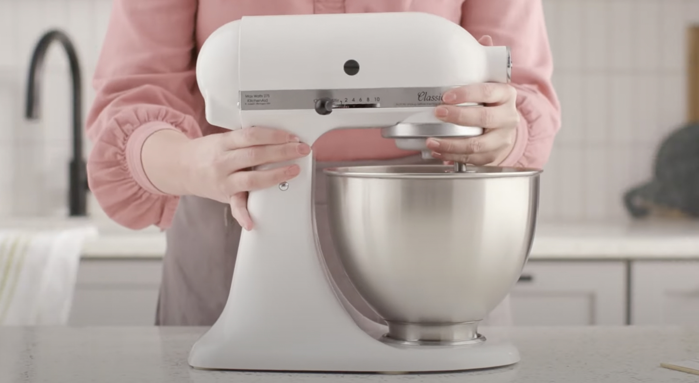 Person holding white, KitchenAid® stand mixer with stainless steel bowl Person holding white, KitchenAid® stand mixer with stainless steel bowl