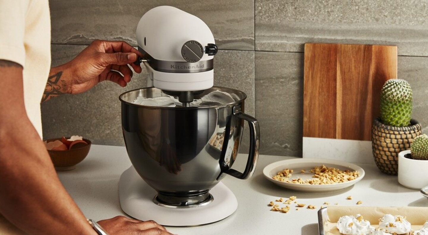 Person adjusting speed on white KitchenAid® stand mixer  Person adjusting speed on white KitchenAid® stand mixer