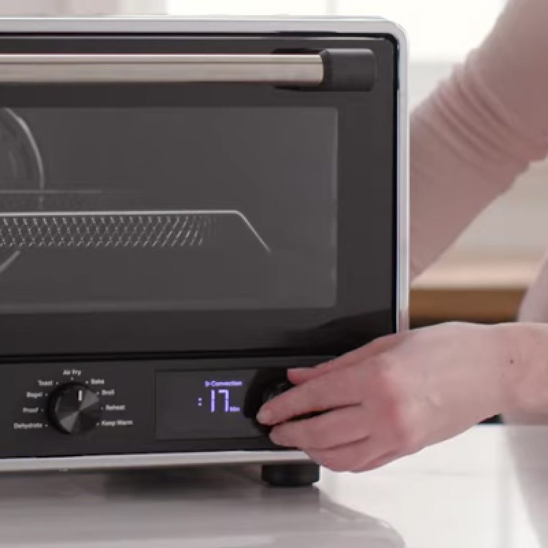 Close-up of person setting air fryer cooking time. 
