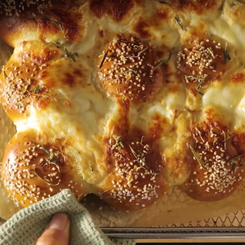 Close-up of hand removing air fryer basket full of bread.