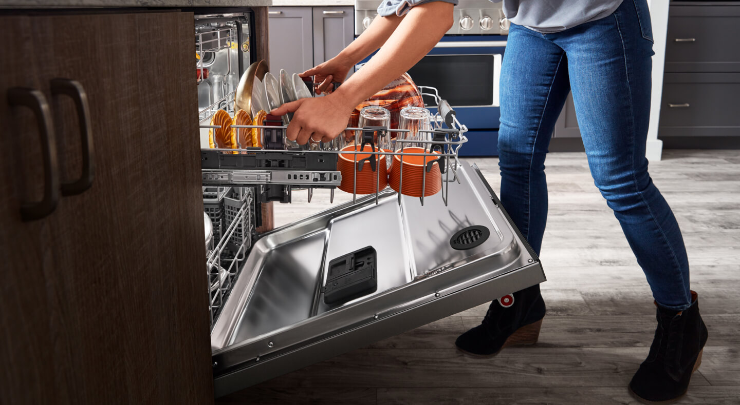 Person adjusting upper rack height of a loaded dishwasher with a third rack Person adjusting upper rack height of a loaded dishwasher with a third rack