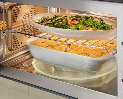 Meal on top rack and another meal on the turntable inside a microwave