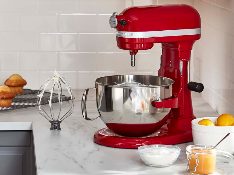KitchenAid® stand mixer next to a wire whip accessory with stiff egg white peaks and frosted muffins in modern kitchen. KitchenAid® stand mixer next to a wire whip accessory with stiff egg white peaks and frosted muffins in modern kitchen.