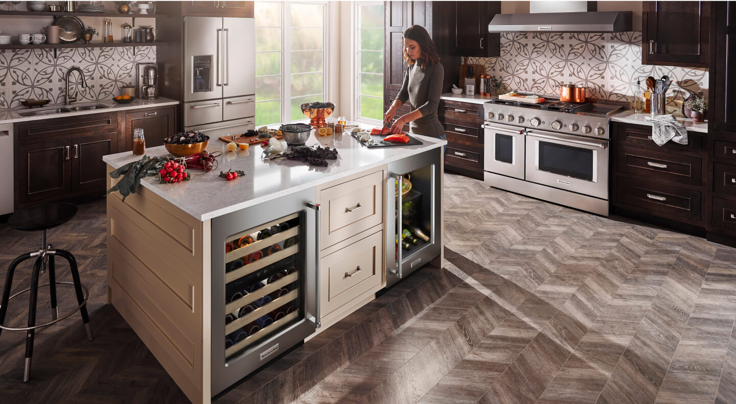 Woman cooking in a kitchen with stainless steel KitchenAid® appliances Woman cooking in a kitchen with stainless steel KitchenAid® appliances