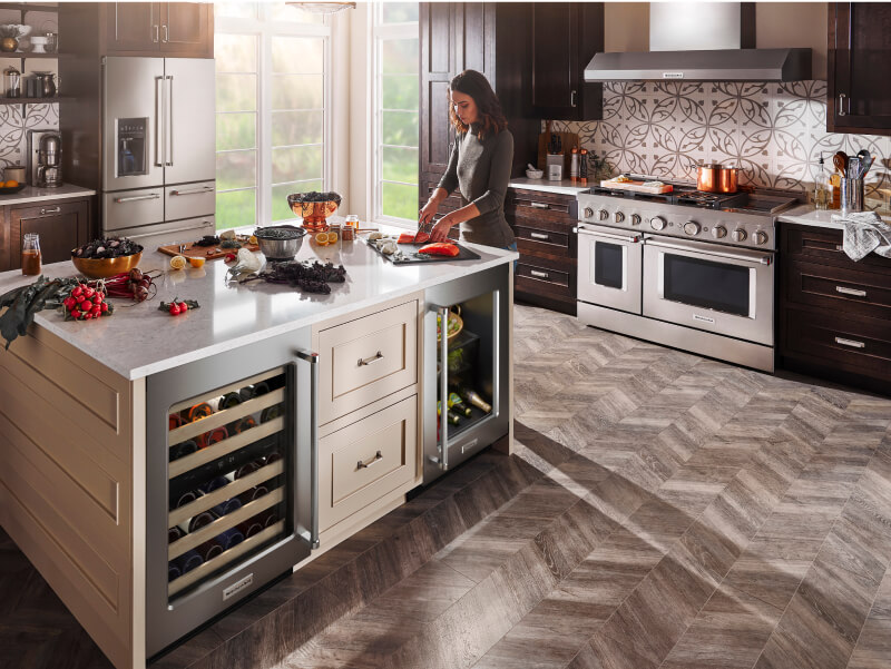 Woman cooking in a kitchen with stainless steel KitchenAid® appliances Woman cooking in a kitchen with stainless steel KitchenAid® appliances