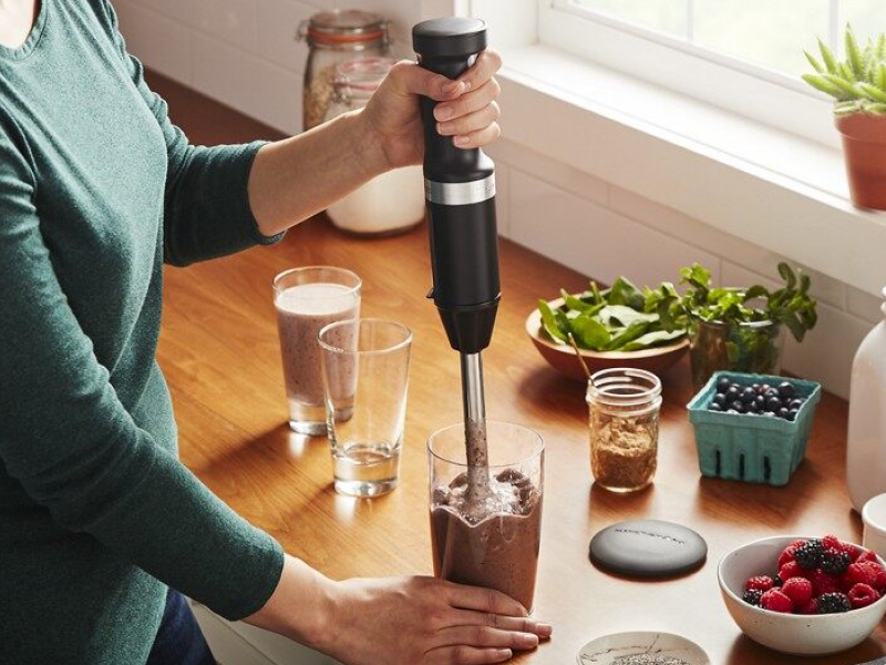 Person blending smoothie with immersion blender