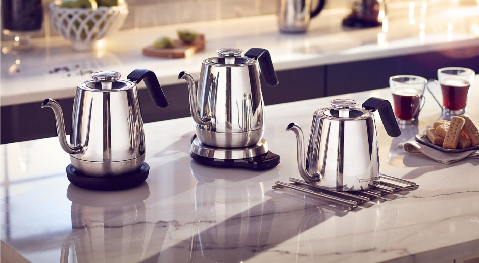 Three KitchenAid® electric tea kettles on the island next to cups of tea and cookie tray. Three KitchenAid® electric tea kettles on the island next to cups of tea and cookie tray.