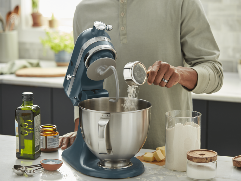 Person adding ingredients into a KitchenAid® stand mixer Person adding ingredients into a KitchenAid® stand mixer
