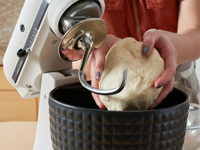 Woman removing a ball of dough from a KitchenAid® stand mixer Woman removing a ball of dough from a KitchenAid® stand mixer