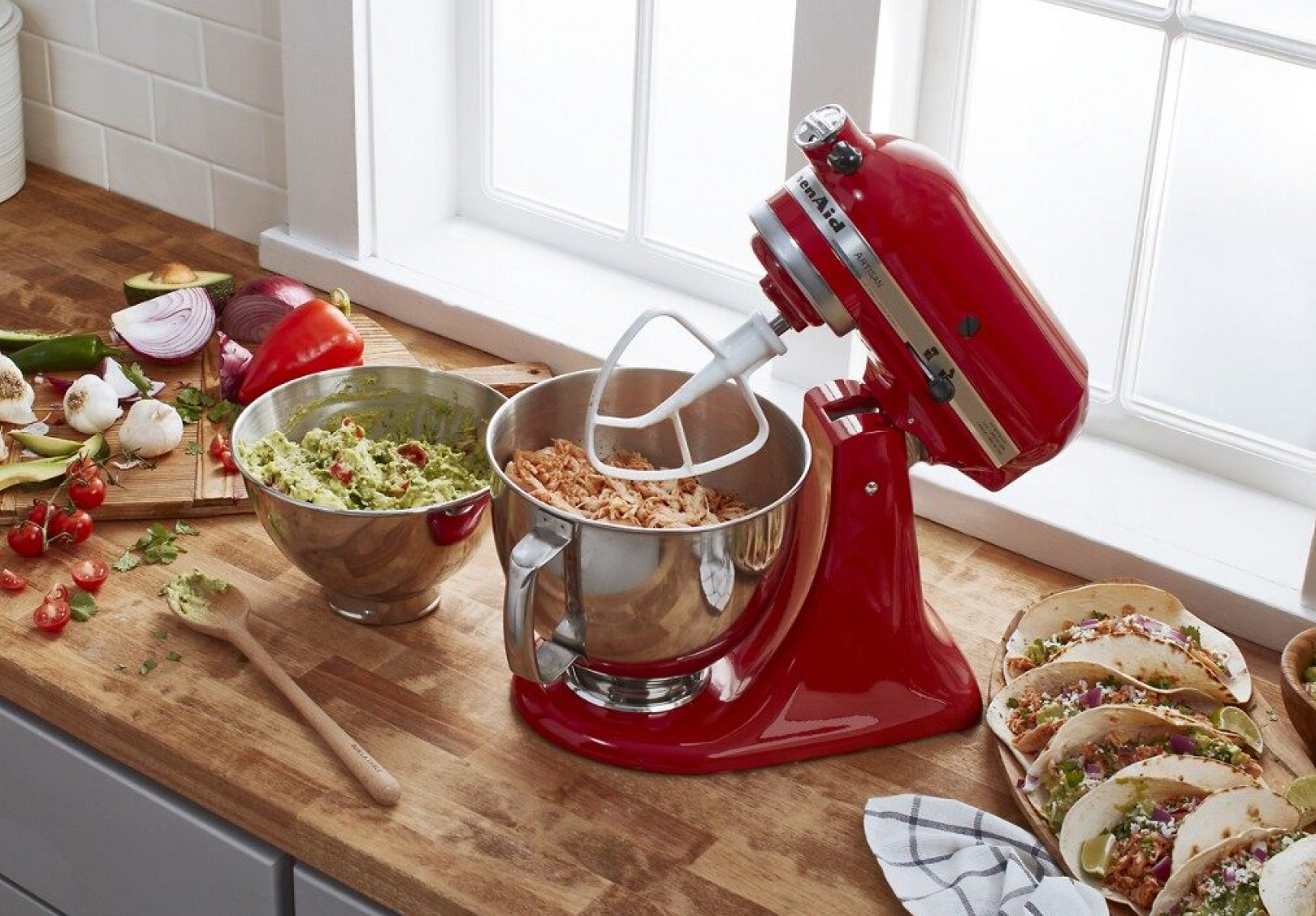 Red stand mixer with paddle attachment above a bowl of shredded chicken Red stand mixer with paddle attachment above a bowl of shredded chicken