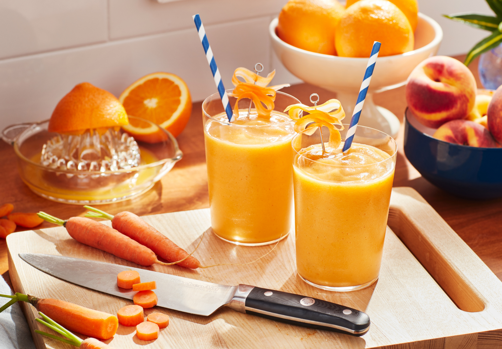 Glasses of orange juice with decorative straws on cutting board with carrots Glasses of orange juice with decorative straws on cutting board with carrots