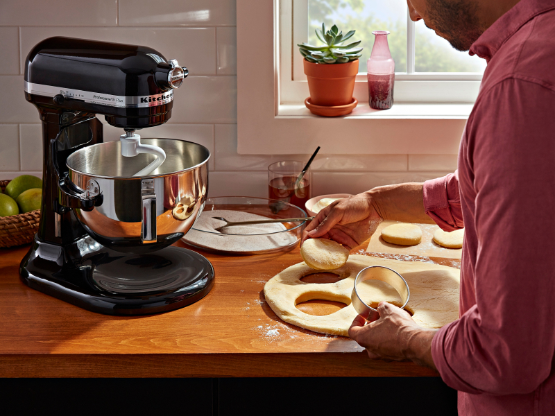 Person using a biscuit cutter to cut biscuit shapes into bread dough Person using a biscuit cutter to cut biscuit shapes into bread dough