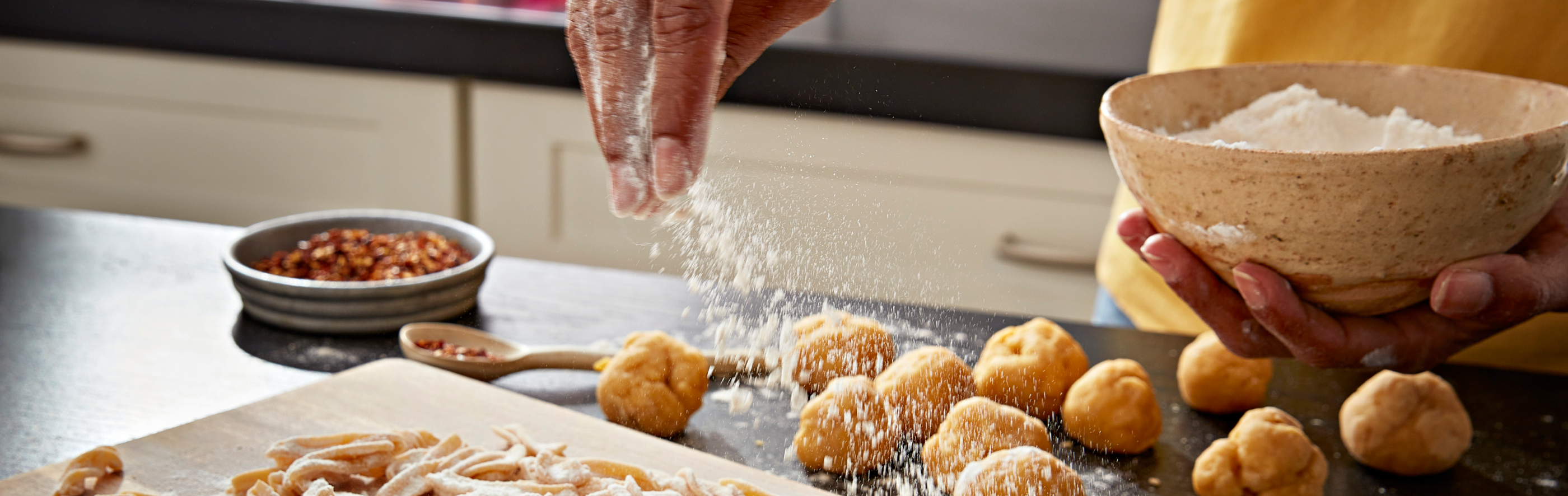A person sprinkling flour over dough