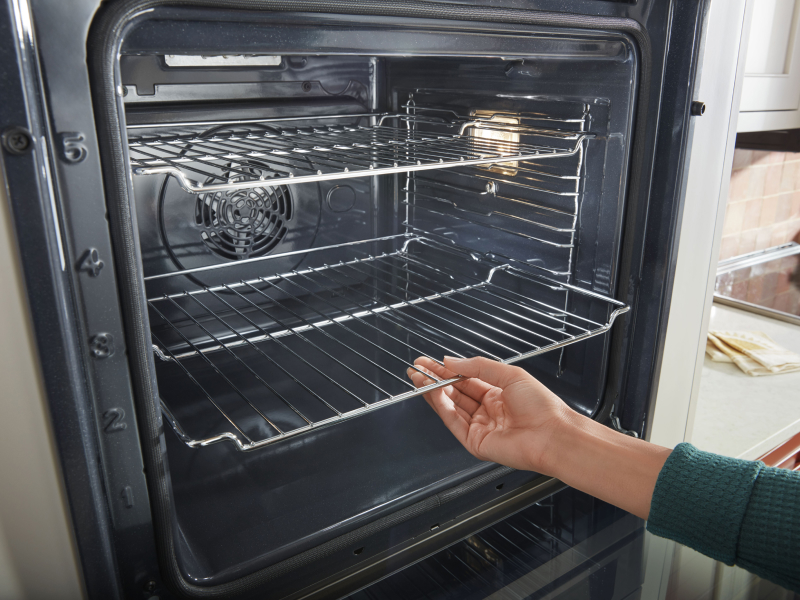 Person adjusting the racks inside an oven