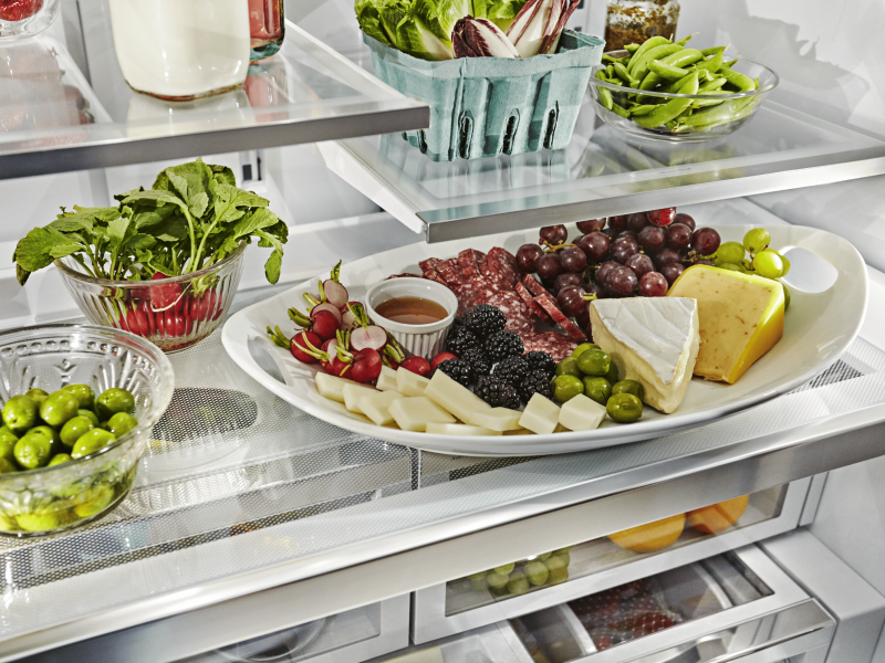 A slide-out tray with grapes, salami, olives, fruit and cheese.