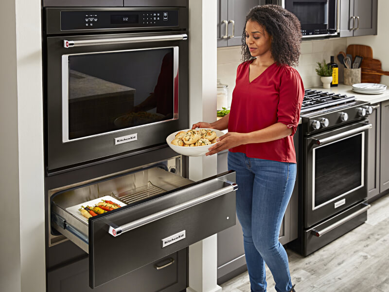 Woman placing a bowl of dough in a KitchenAid® oven warming drawer