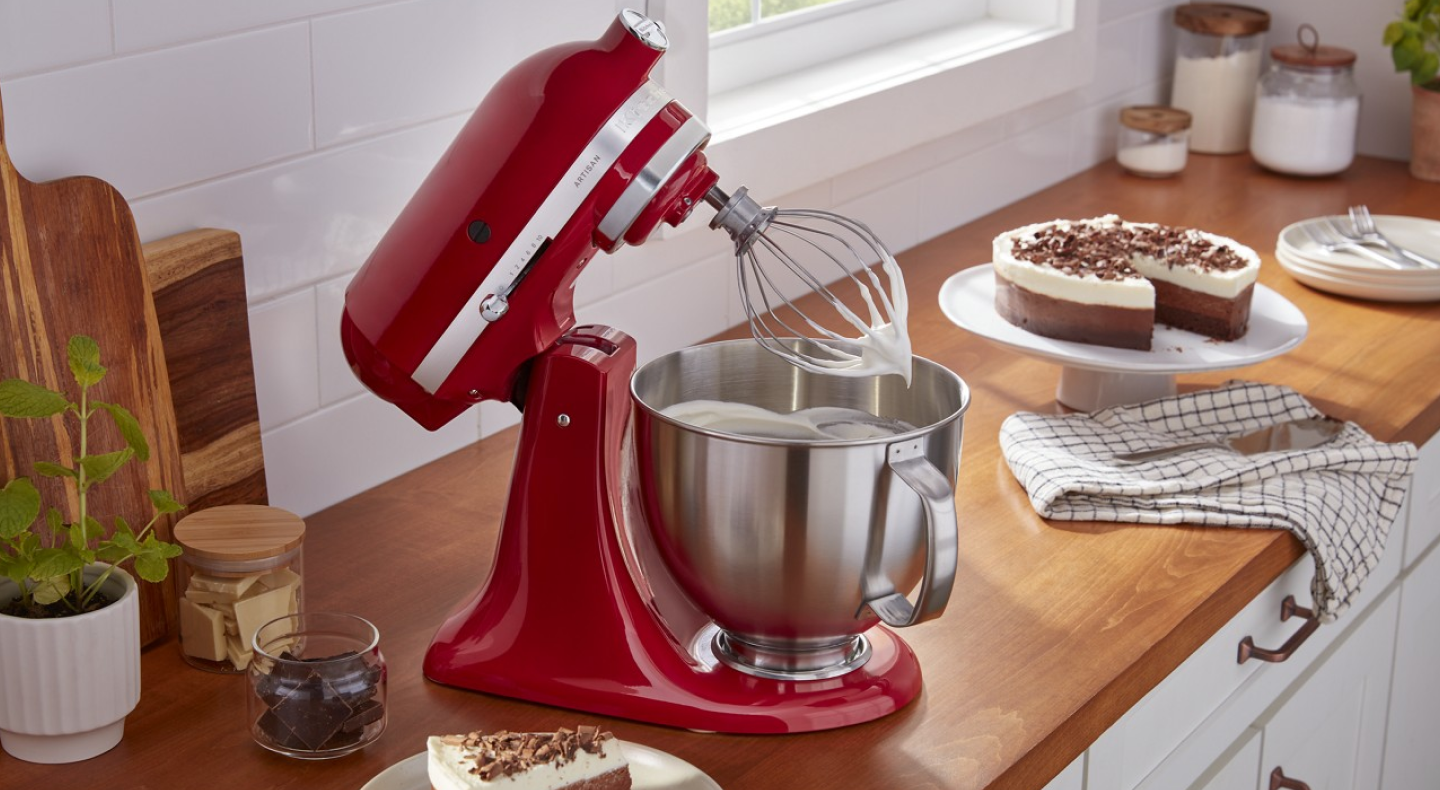 Red KitchenAid® stand mixer whipping cream next to pie on counter Red KitchenAid® stand mixer whipping cream next to pie on counter