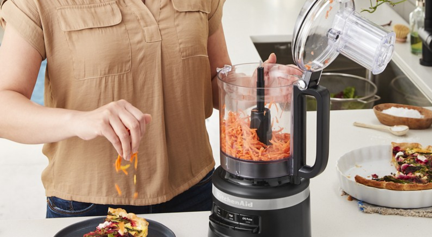 Person shredding carrots in a black food processor Person shredding carrots in a black food processor