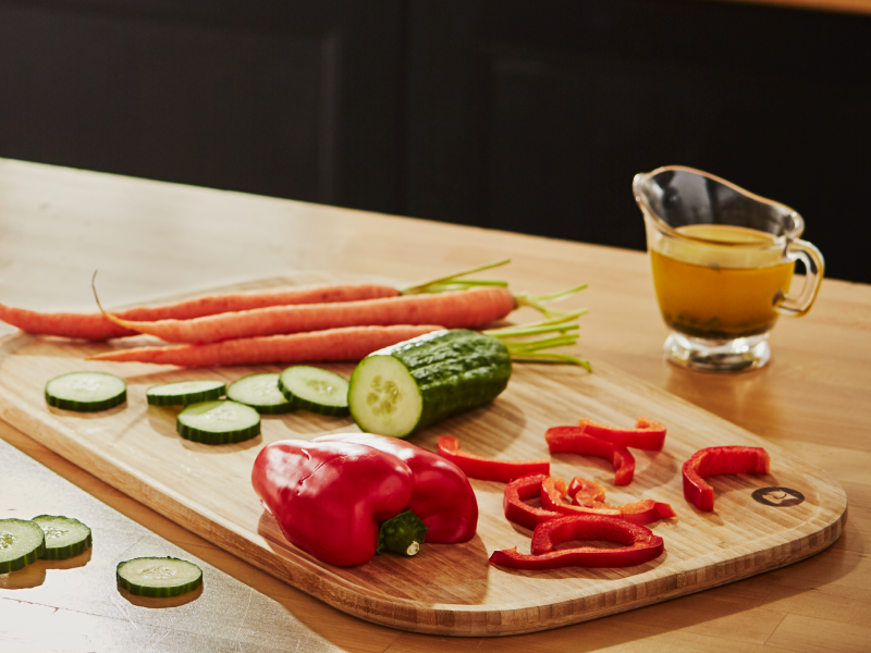 Cucumbers, peppers and carrots on a wooden cutting board