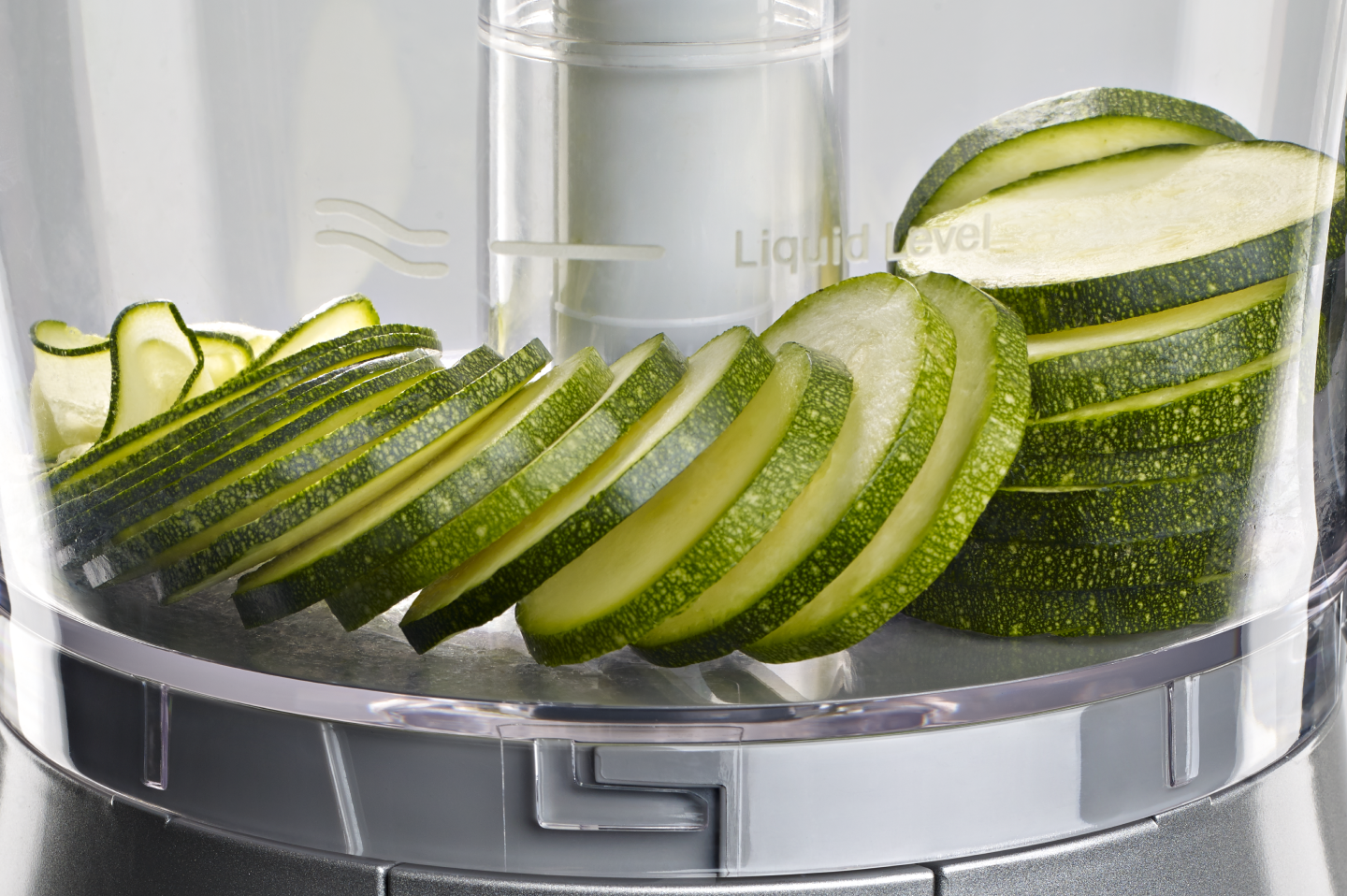 Close up image of sliced cucumbers inside a food processor work bowl Close up image of sliced cucumbers inside a food processor work bowl