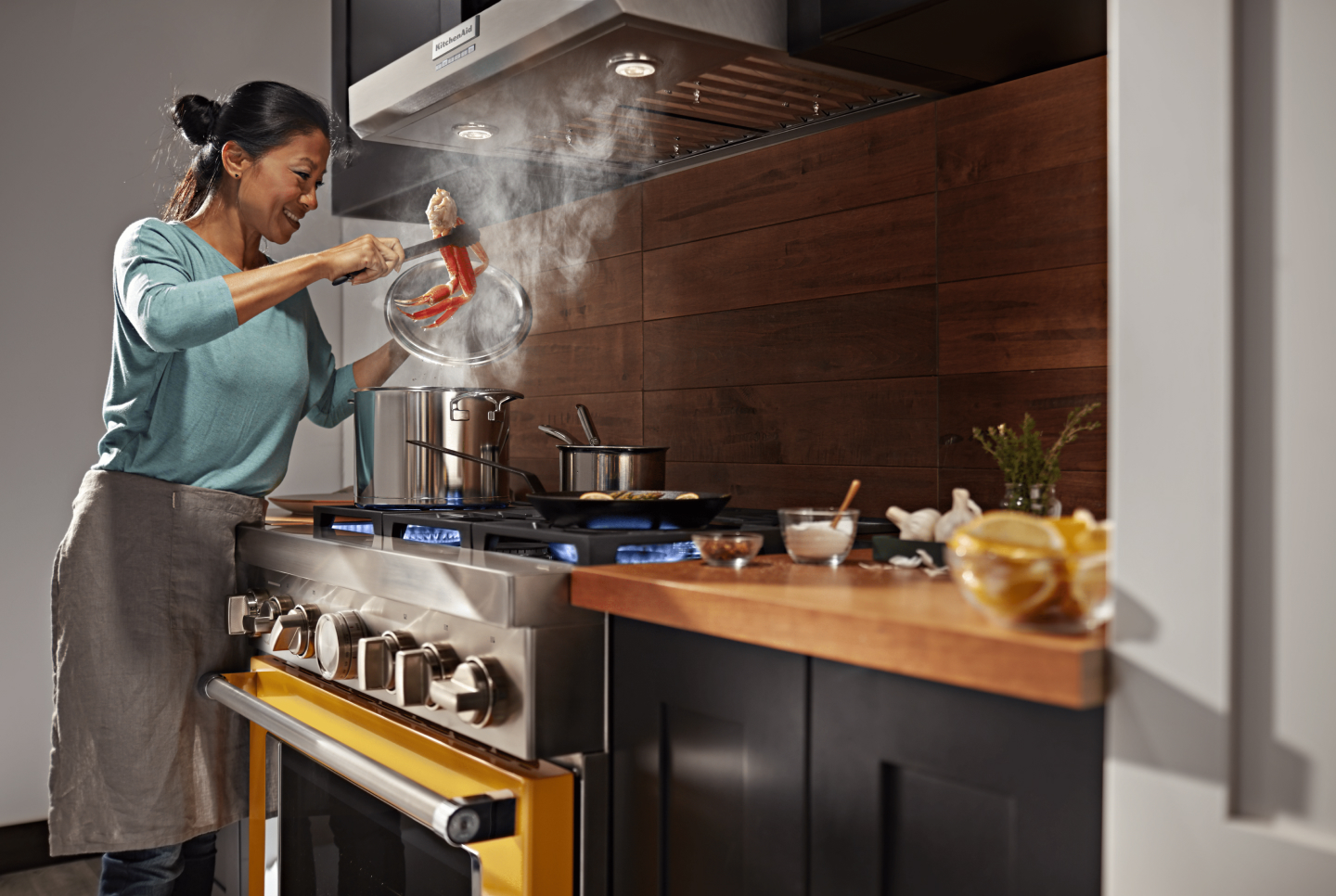 Range hood venting steam as person cooks on range below