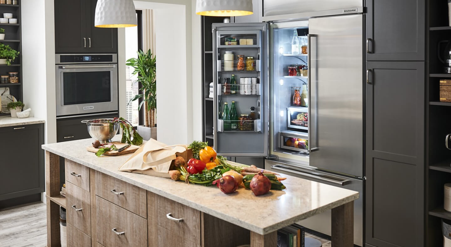 Open KitchenAid® French door refrigerator behind island with fresh produce Open KitchenAid® French door refrigerator behind island with fresh produce
