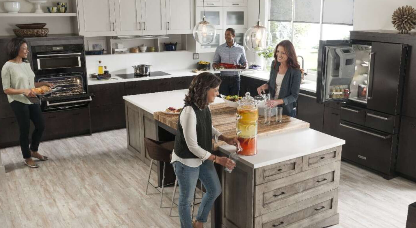 People gathering and cooking in a kitchen with a KitchenAid® 4-door refrigerator People gathering and cooking in a kitchen with a KitchenAid® 4-door refrigerator