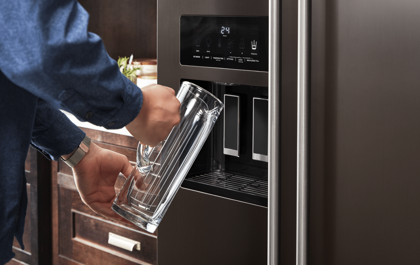 Person filling a pitcher at the refrigerator water dispenser Person filling a pitcher at the refrigerator water dispenser