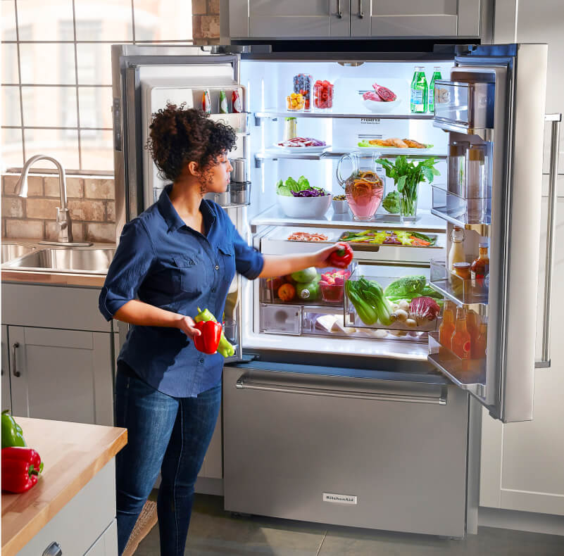 A person placing red and green peppers in a crisper drawer A person placing red and green peppers in a crisper drawer