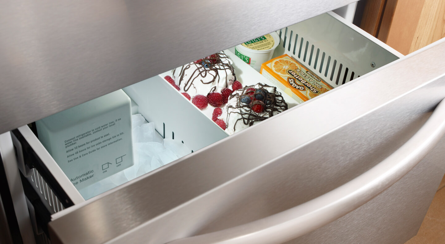 Freezer drawer slightly ajar with ice cream and sorbet inside Freezer drawer slightly ajar with ice cream and sorbet inside