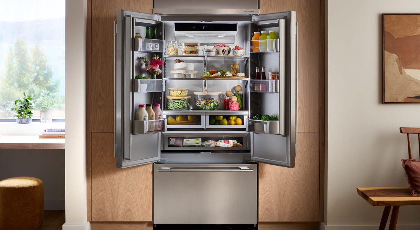 Open KitchenAid® French door refrigerator built into brown cabinetry