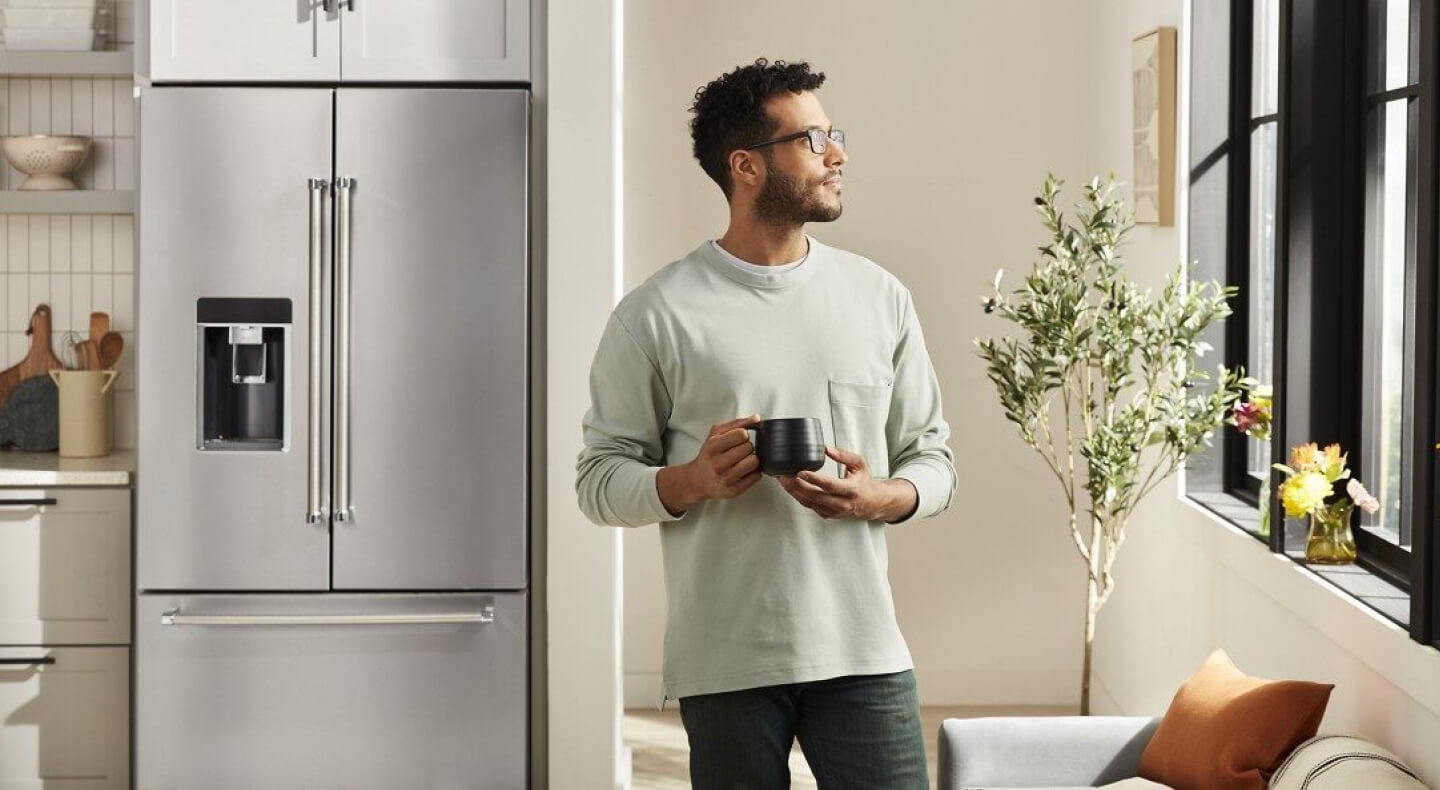 Person holding a coffee mug inside a kitchen