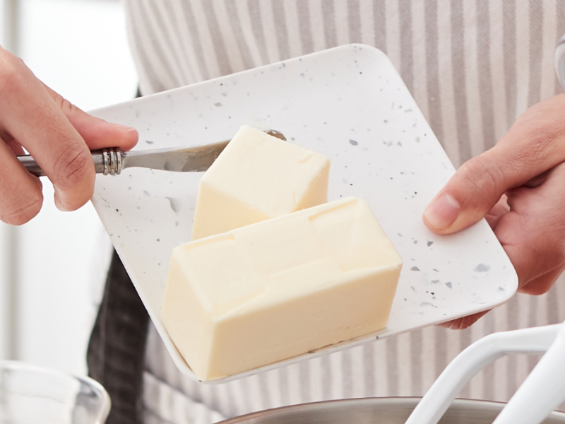Person adding butter to a KitchenAid® stand mixer bowl Person adding butter to a KitchenAid® stand mixer bowl