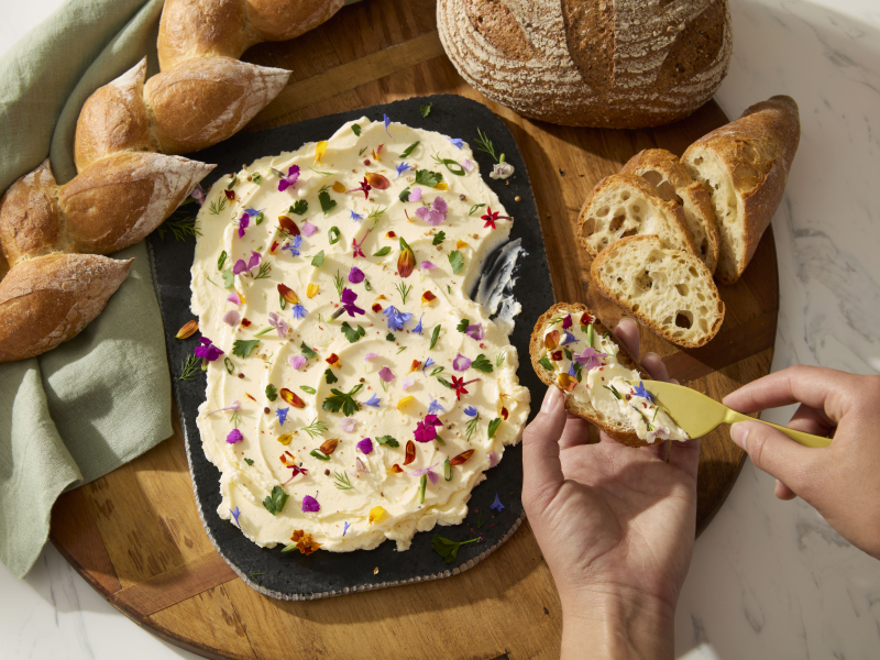 A person topping a loaf of baked bread with a homemade spread A person topping a loaf of baked bread with a homemade spread